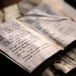 Altes, aufgeschlagenes Tagebuch mit vergilbten, handbeschriebenen Seiten auf einem Holztisch