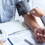 Medizinische Fachkraft misst einem Patienten mit einer Manschette den Blutdruck