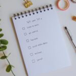 Spiral-Notizblock mit handgeschriebener Selbstfürsorge-Liste, daneben Stift und Eukalyptuszweig