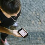 Joggerin schaut von oben gesehen auf ihr Smartphone mit Fitness-App