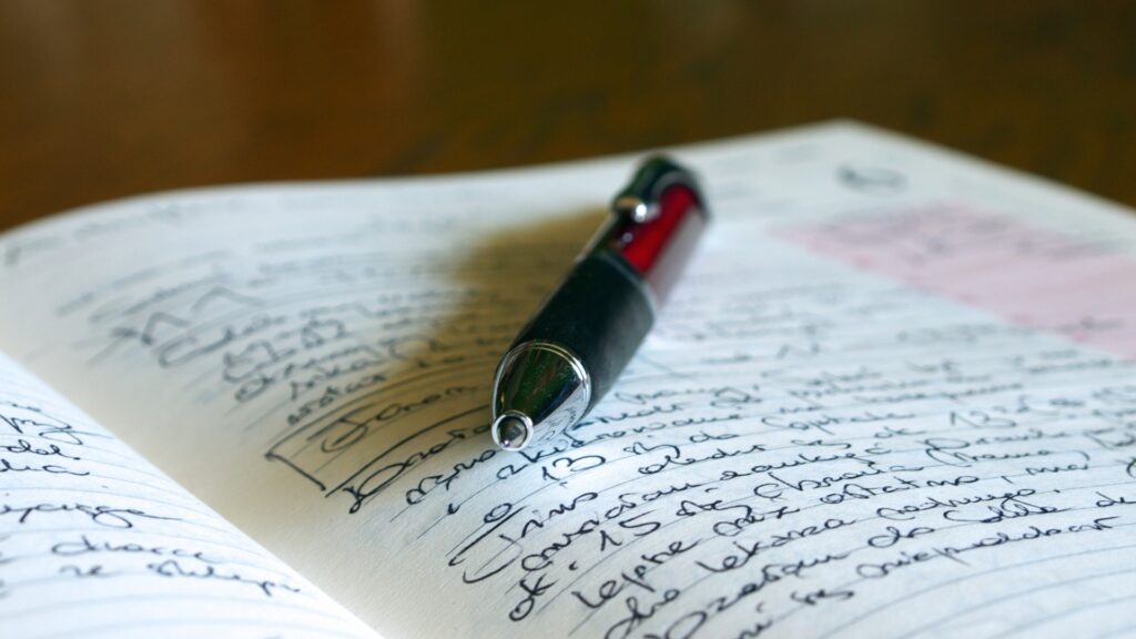 Rot-schwarzer Füller liegt auf einem handschriftlich beschriebenen Tagebuch